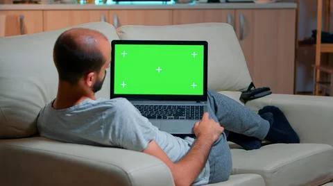 Tired man lying on sofa working on computer Stockfoto's