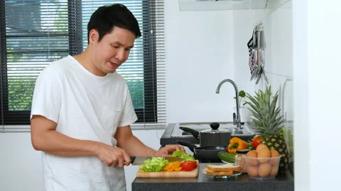 Tired man with preparing vegetables to cooking in the kitchen at home Stock Footage 170708702