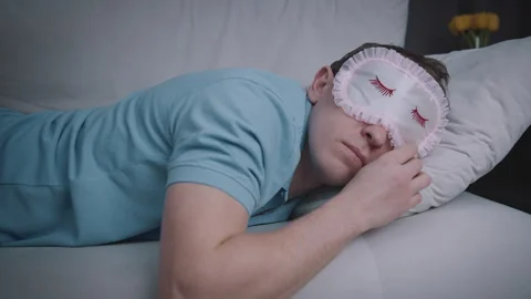 Tired Man Resting on Sofa with Sleep Mask at Night Stock Footage 329959365