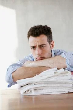 A tired man resting on a stack of folded laundry Foto stock