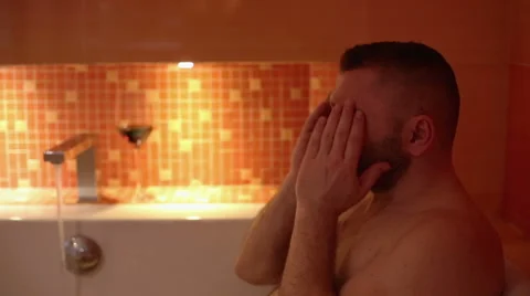 Tired man is seated in bath  Stock Footage 61925895