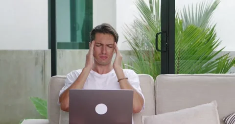 Tired man suffer from headache while remotely work at computer at home. Business Stock Footage 237236681