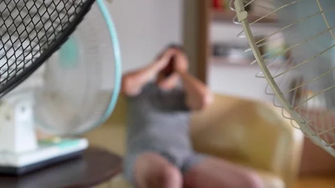 Tired man sweating and suffering from heatwave, sitting on sofa surrounded .. Stock Footage 315019031