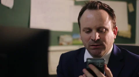 Tired man using cell phone in office Stock Footage 61348820