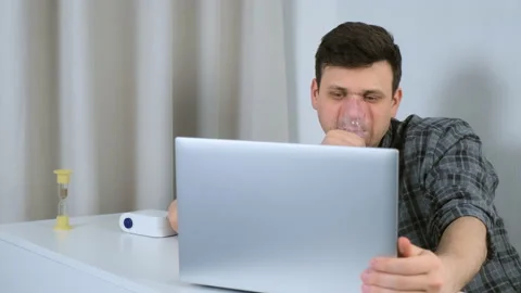 Tired man is using nebulizer and inhaler for treatment cure working on laptop. Stock Footage 152716157