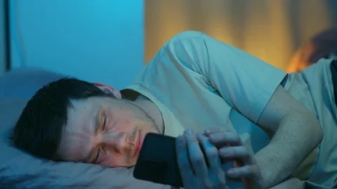 Tired man using a smartphone at night before sleeping Vídeos de archivo 337892821