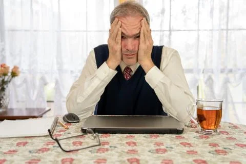 Tired man working on computer in dining room Stock Photos