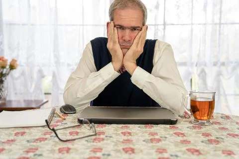 Tired man working on computer in dining room Stock Photos