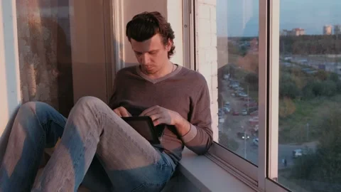 Tired man working on laptop and falls asleep sitting on balcony with city view Stock Footage 102449809