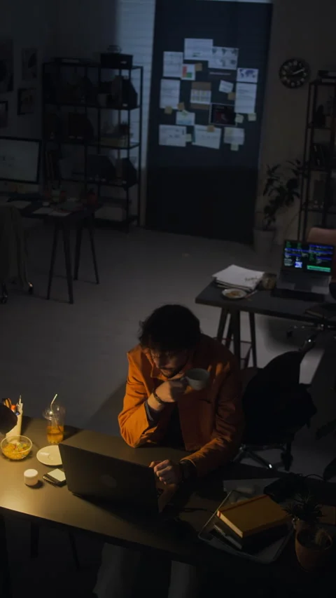 Tired Man Working Late on Laptop Drinking Coffee in Dark Office Stock Footage 338418382