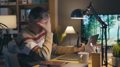 Tired man working at night and suffering from headache Stock Footage 306126433