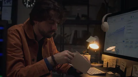 Tired Man Working Overtime in Office Eating Takeout Food at Night Stock Footage 338417414