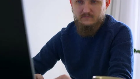 A tired man works at a computer, a mug of coffee is on the table. A brutal bald Stock Footage 170746019