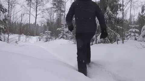Tired middle aged man walks away in snow shoes in forest snow covered Stock Footage 231250093
