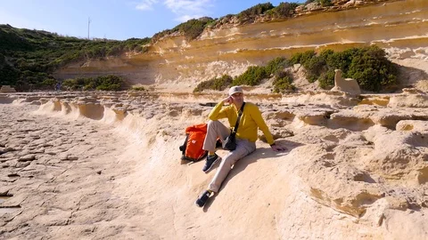 A tired middle-aged man in a yellow sweater and cap sits against a background of Stock Footage 102046544