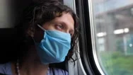 A Tired Middle-Aged Woman In A Protective Blue Mask Looks Out The Window Of A Stock Footage
