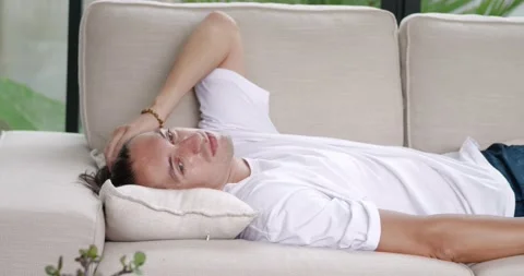 Tired millennial man falls down on couch. Exhausted young male person wants to Stock Footage 238501810