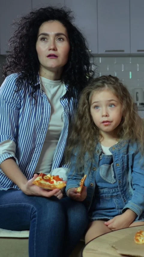 Tired Mother And Daughter Watching Tv In Kitchen, Sitting On Couch With Pizza Stock-Footage 341442453