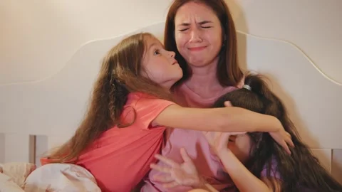 Tired mother sits in bed while two siblings hug her and show different emotions Stock Footage 330750112