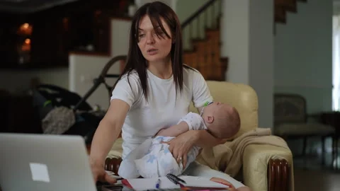 Tired mother working on laptop while holding sleeping baby 스톡 동영상 331303000