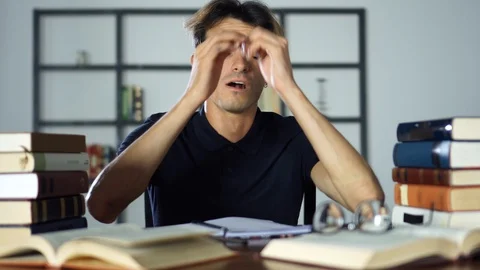 A tired nerd falling asleep on a bunch of books Stock Footage 93259440