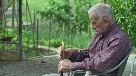 Tired old man sitting alone outdoor in countryside green background Video stock 40299458