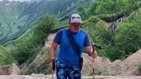 A tired one-armed guy with trekking poles goes hiking Stock-Footage 316879543