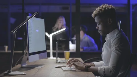 Tired or bored man working at computer at night office Stock Footage 125690344