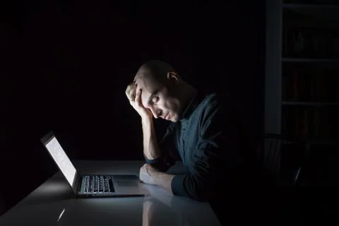 Tired or exhausted man at computer late in the evening with closed eyes. Stock Photos