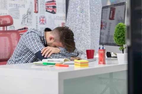 Tired overworked businessman sleeping over a desk at job in his office Stock Photos