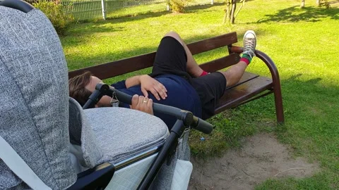 Tired parent laying down on a bench in t... | Stock Video | Pond5