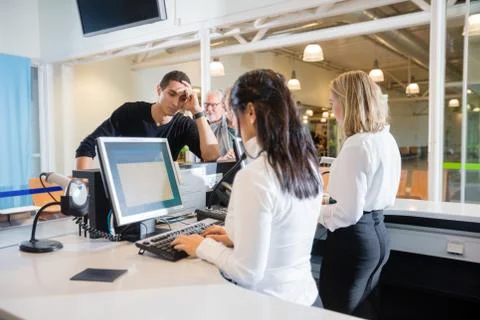 Tired Passenger Waiting At Check-in While Staff Using Computer Stock Photos