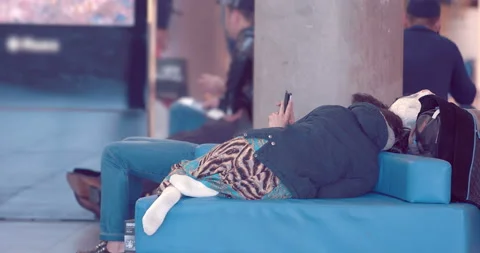 Tired passengers sleeping on sofas waiting for departure fron airport Stock Footage 119596506