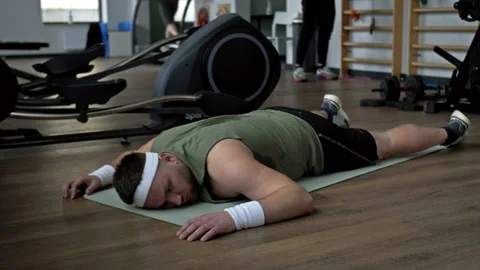 Tired from physical activity, a young overweight man lies prone on a karemat in Stock Footage 239652385