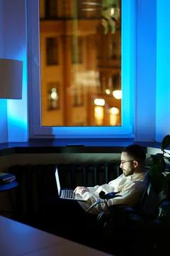 Tired programmer in dark office work on laptop. Workaholic businessman typing on Stock Photos