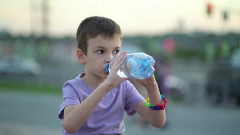 Tired schoolboy drinks fresh drinking water from a plastic bottle. The boy Stock Footage 204101614