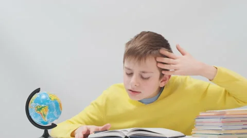 Tired schoolboy sits next to stack of copybooks and fell asleep Video stock 172489328