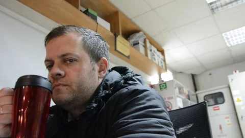 Tired security guard drinks a hot drink from red mug. steam rises over a mug. Stock Footage 122595478