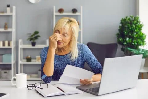 Tired senior woman receiving bankruptcy notification or rejection letter and Stock Photos