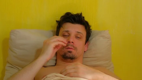 Tired sick man is waking up with headache, hangover, portrait closeup. Video stock 128958688
