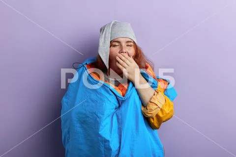 Tired sleepy tourist woman hiker in a sleeping bag closing her mouth with a hand Stock Photos