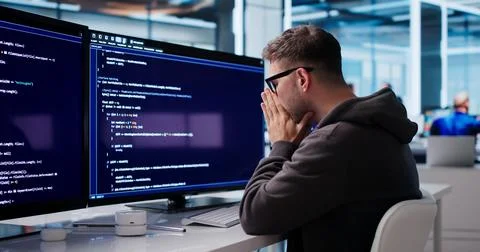 Tired Software Engineer Struggles With Coding Tasks At His Office Desk. Stock Photos