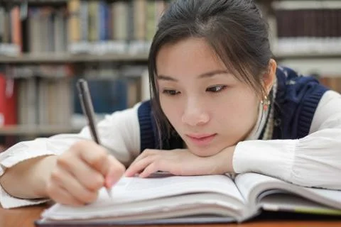 Tired student doing homework in library Stock Photos