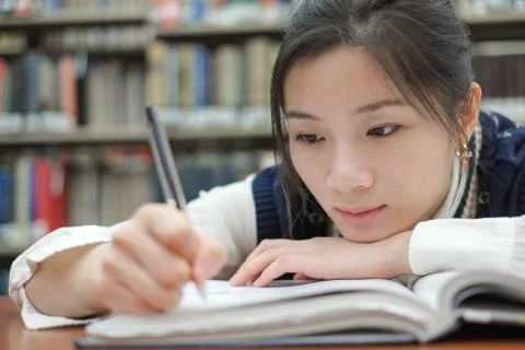 Tired student doing homework in library Stock Photos
