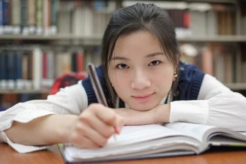 Tired student doing homework in library Stock Photos