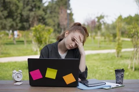 Tired student, freelancer sitting at table with closed eyes. Stock Photos