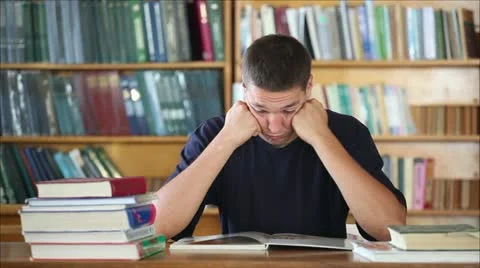 Tired student in the library reading books 3 Stock Footage