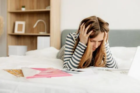 A tired student is preparing for a difficult exam at home using a laptop. Modern Stock-Fotos