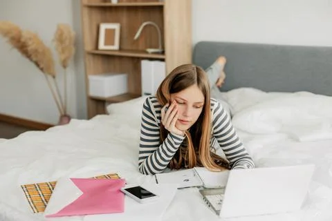 A tired student is preparing for a difficult exam at home using a laptop. Modern Stock Photos
