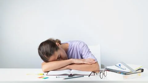 A tired student sleeps on a notebook on the table - before the exam Stock Photos